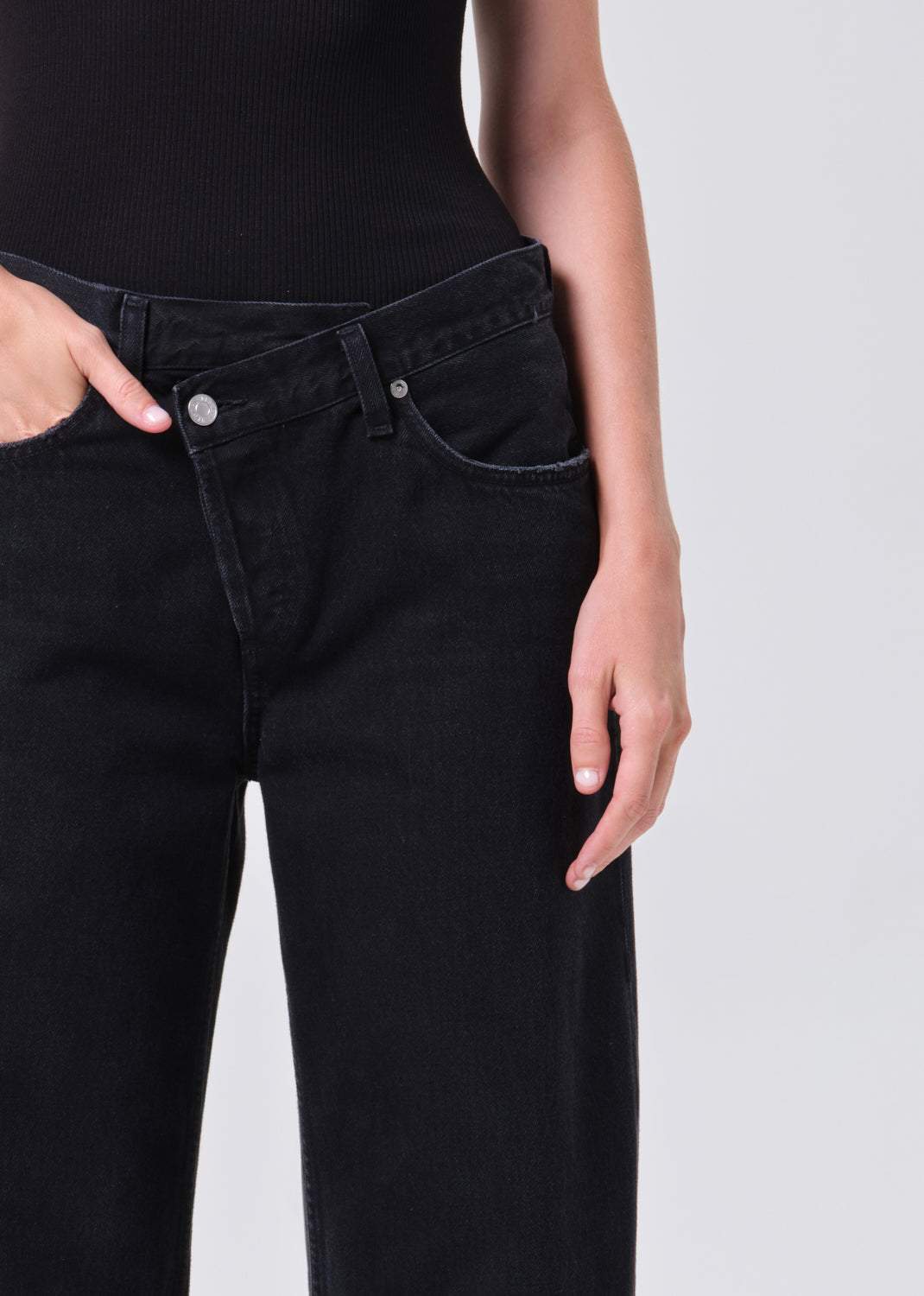 Person wearing black jeans on a plain background