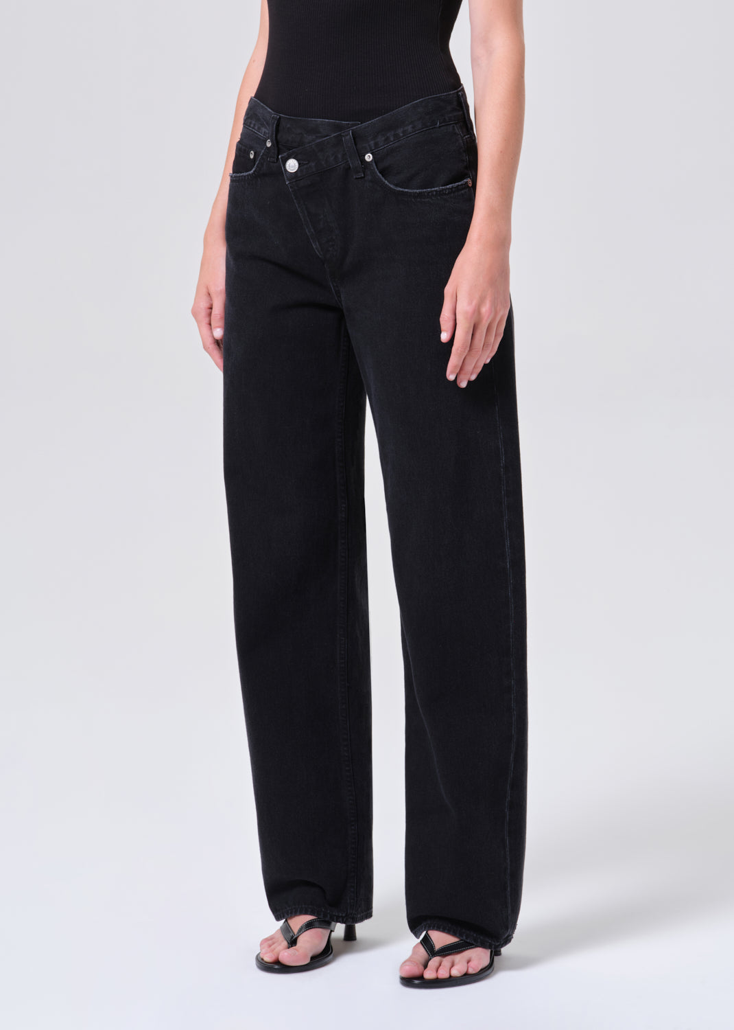 Person wearing black wide-leg jeans on a white background