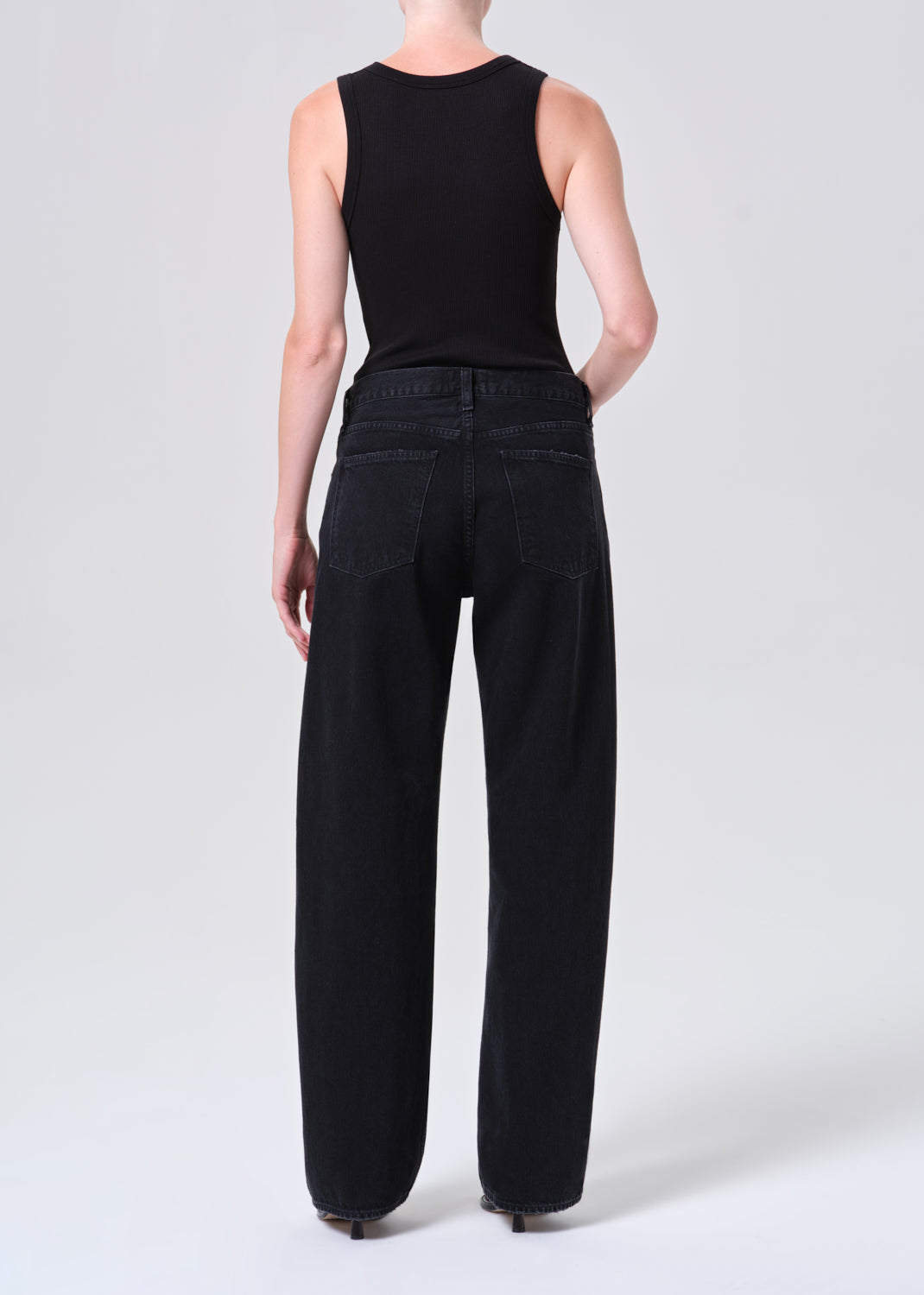 Person wearing black sleeveless top and wide-leg pants on a white background