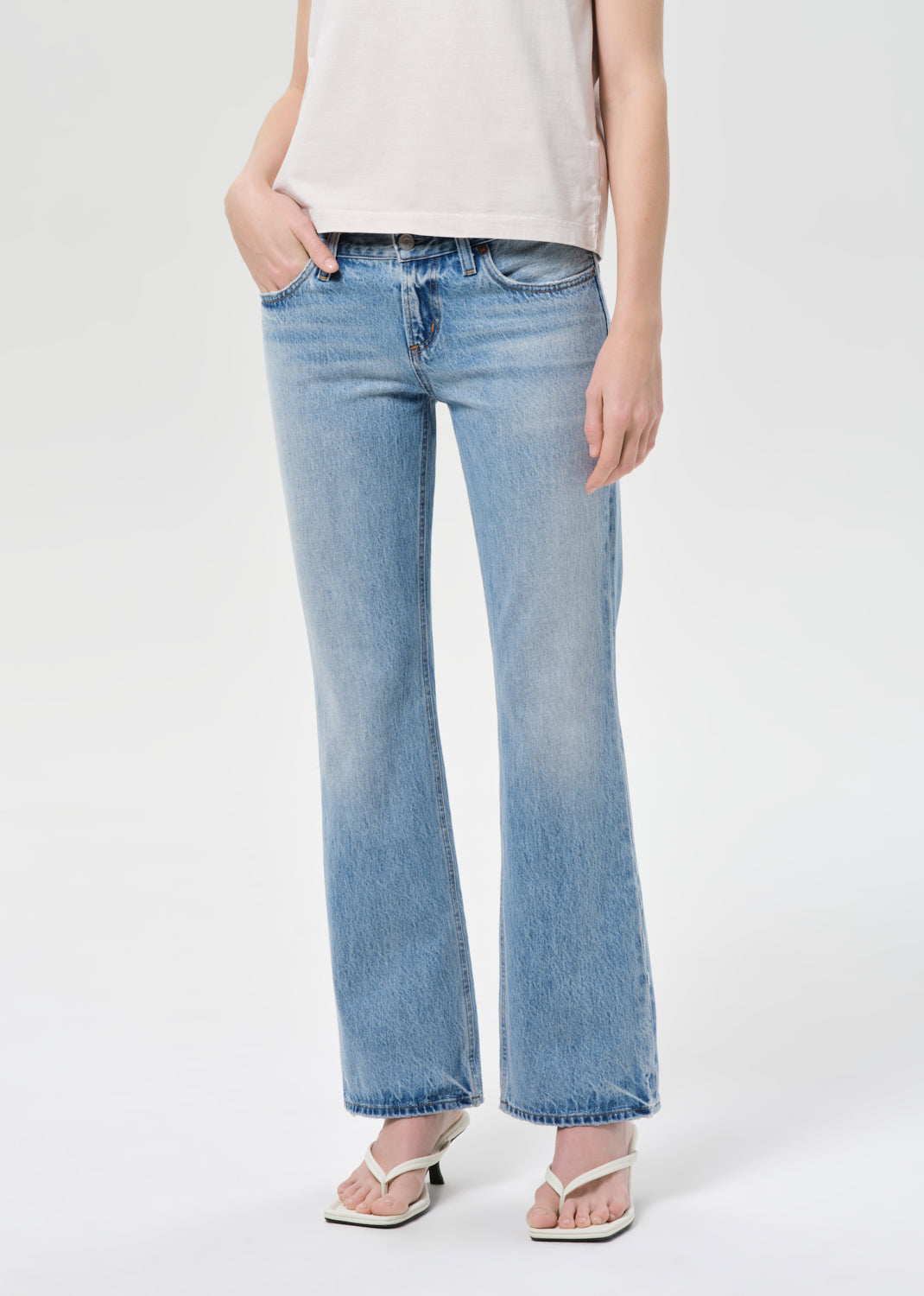 Person wearing light blue jeans and a white top on a white background