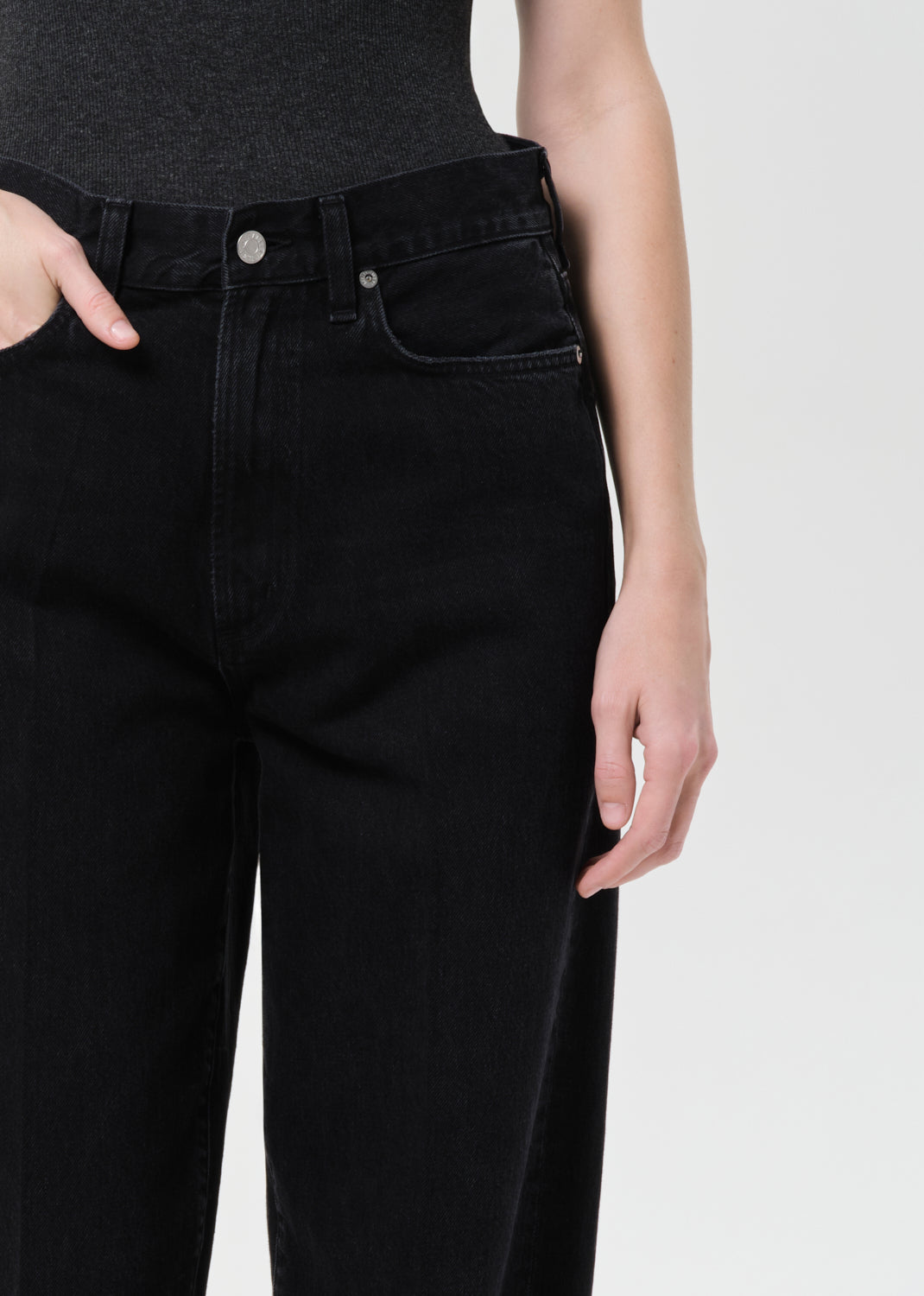 Person wearing black jeans on a plain background