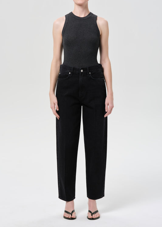 Person wearing a black sleeveless top and black pants on a white background