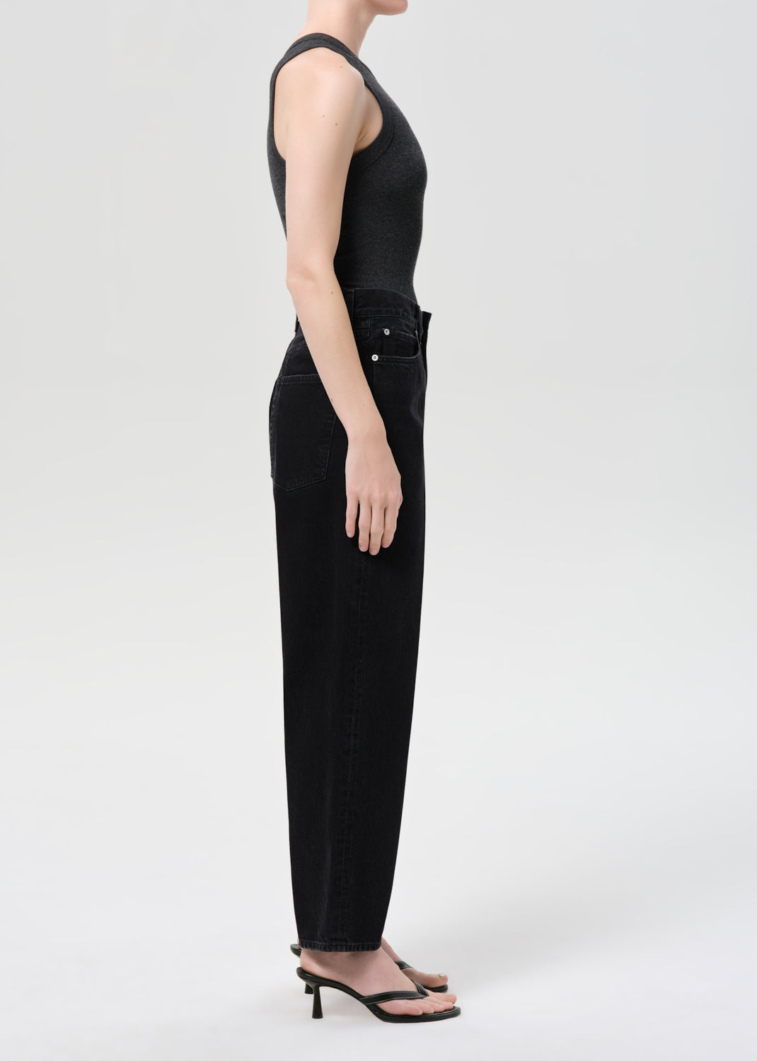 Woman wearing a black sleeveless jumpsuit on a white background