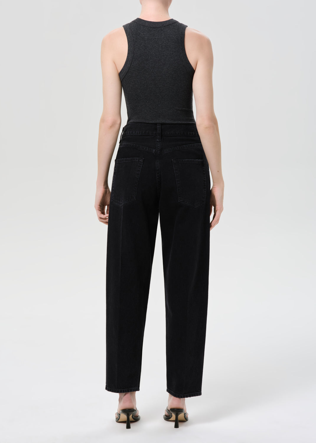 Person wearing a black sleeveless top and pants on a white background