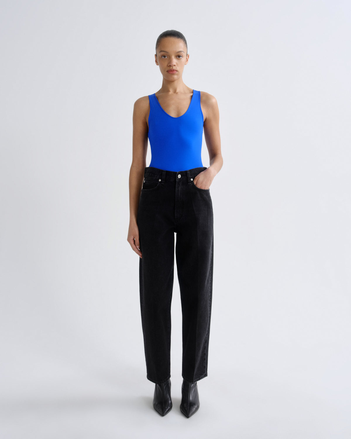 Person wearing a blue tank top and black pants on a white background