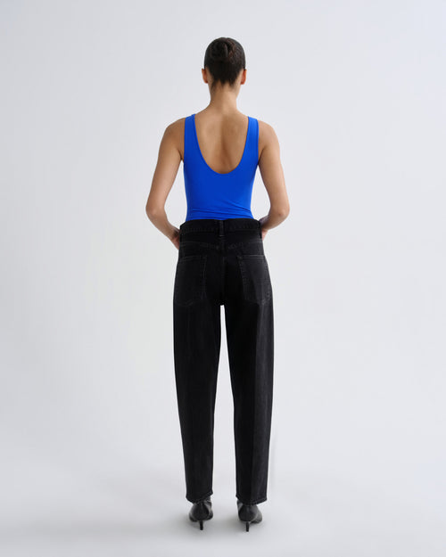 Person wearing a blue tank top and black pants on a white background