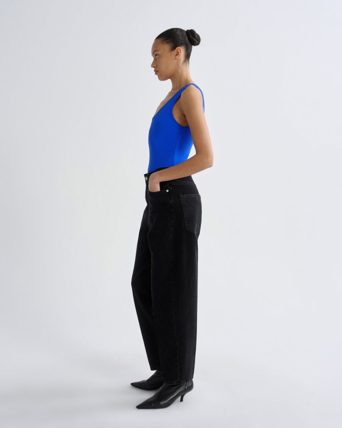 Woman wearing a blue top and black pants on a white background