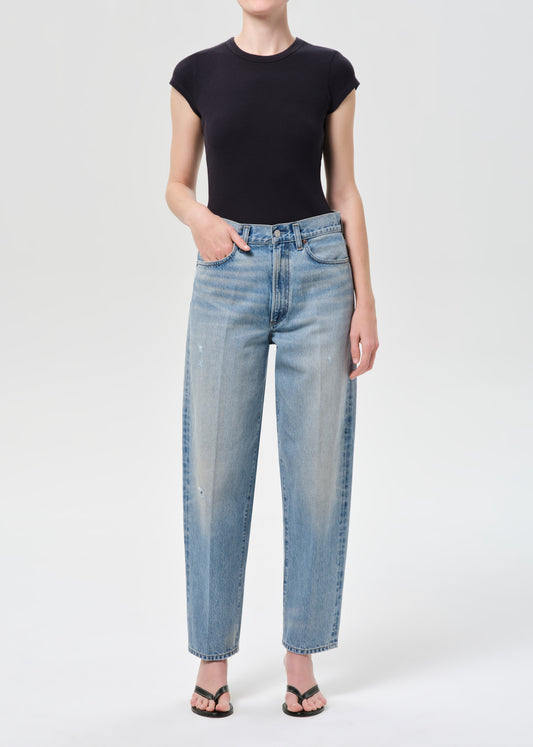 Person wearing a black top and light blue jeans on a white background