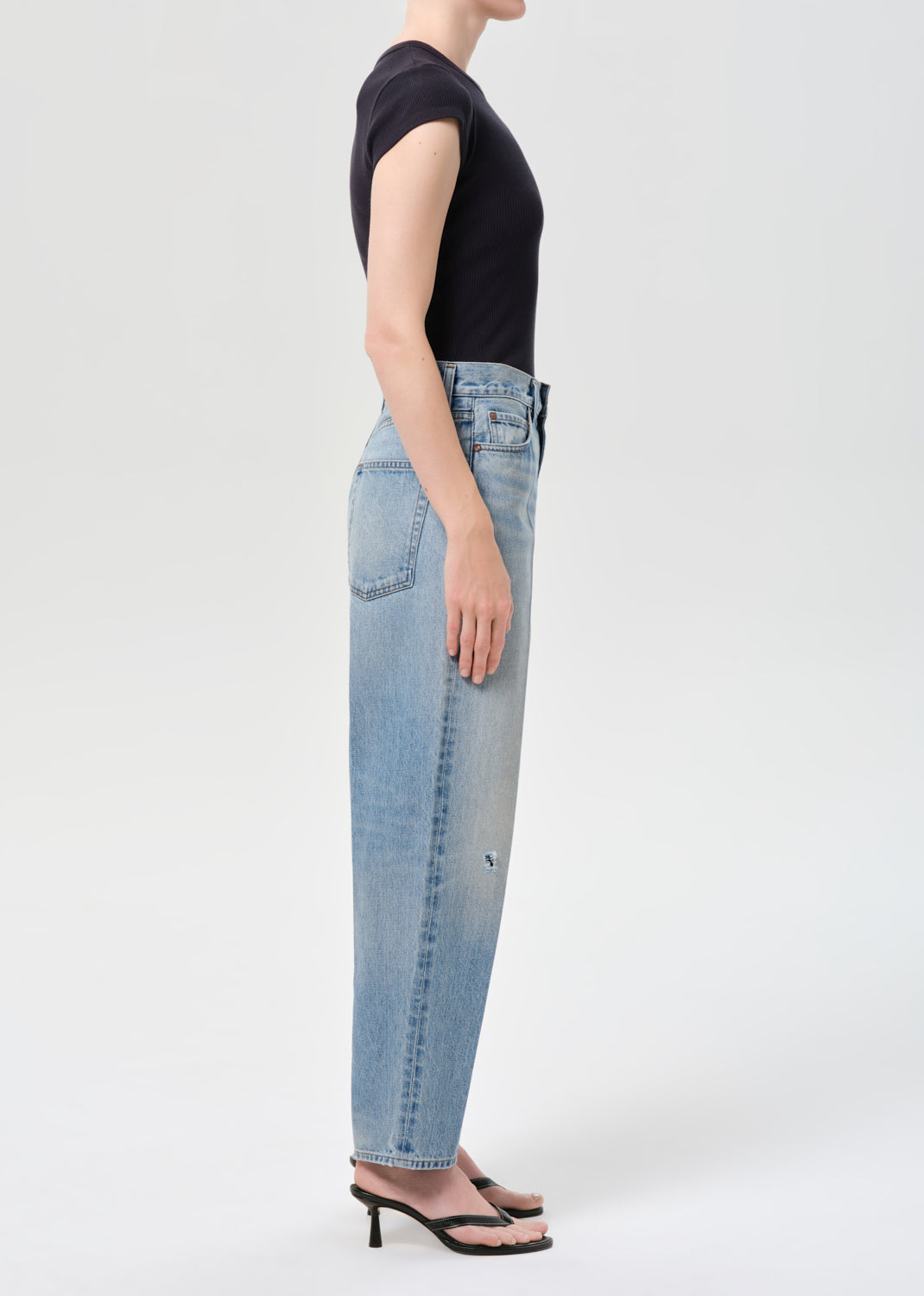 Person wearing light blue jeans and a black top on a white background