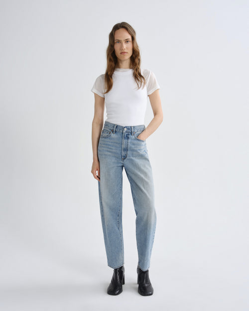 Woman wearing light blue jeans and a white t-shirt on a white background