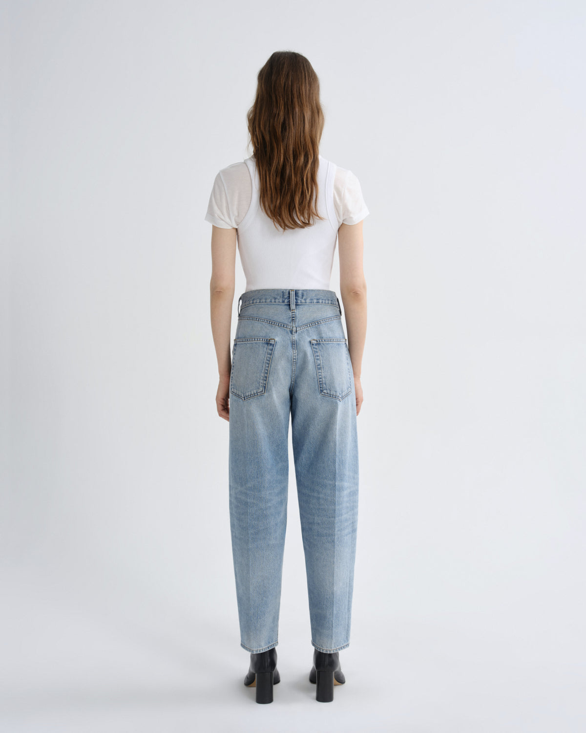 Person wearing light blue jeans and a white shirt on a plain background