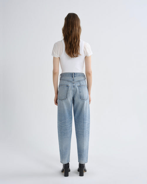 Person wearing light blue jeans and a white shirt on a plain background