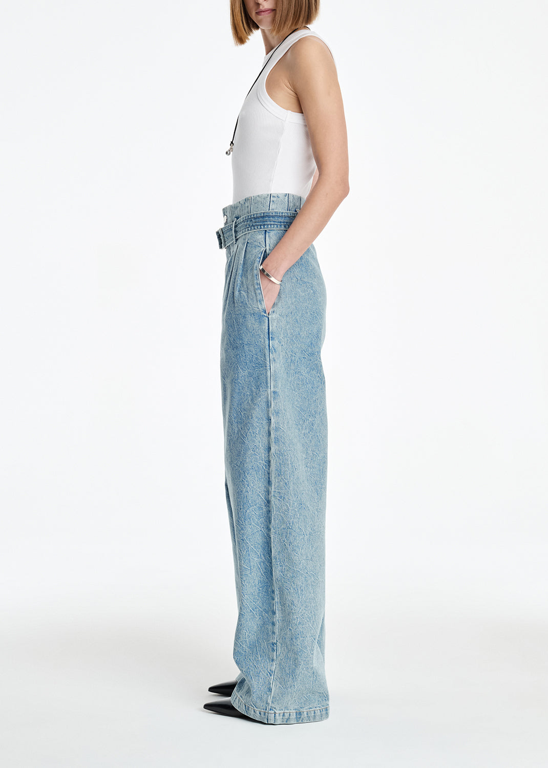 Person wearing light blue jeans and a white top on a white background