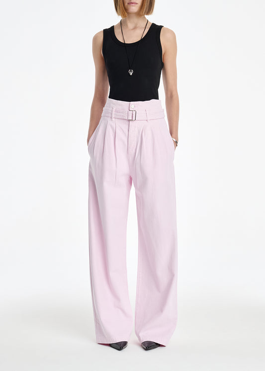 Person wearing a black sleeveless top and light pink pants on a white background