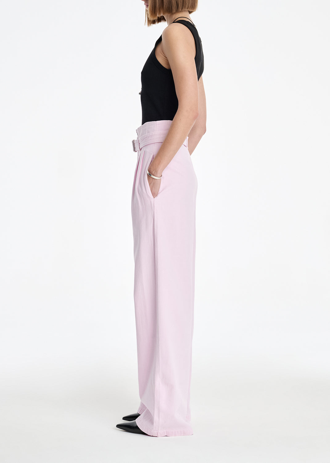 Person wearing light pink pants and a black top on a white background