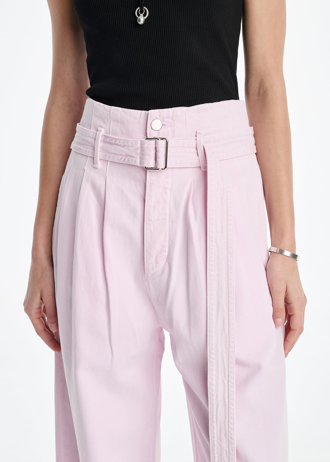 Person wearing light pink pants with a black top on a white background