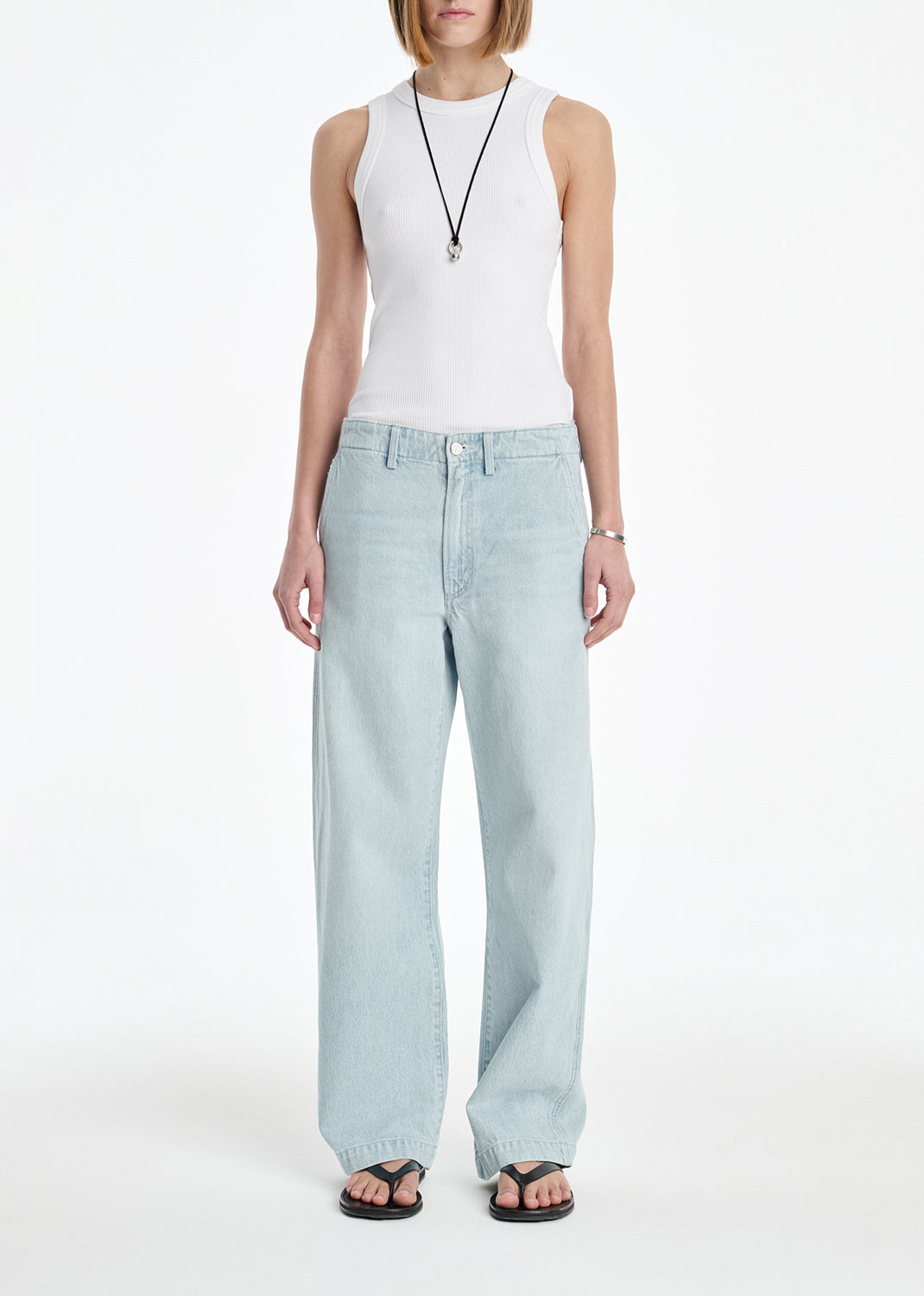 Person wearing a white sleeveless top and light blue jeans on a white background