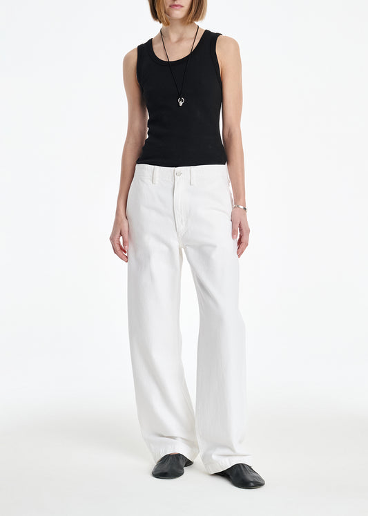 Woman wearing a black sleeveless top and white pants on a white background