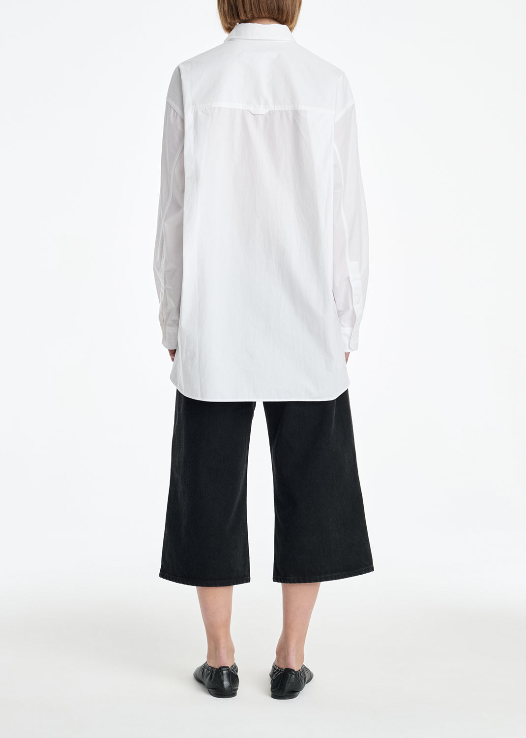 Person wearing a white shirt and black pants on a white background