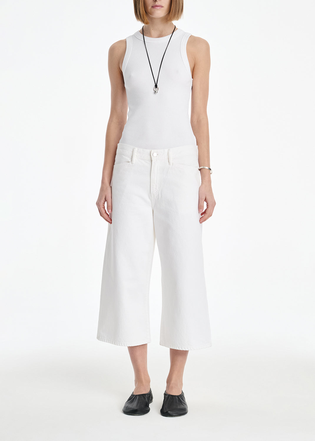 Person wearing a white sleeveless top and wide-leg pants on a white background