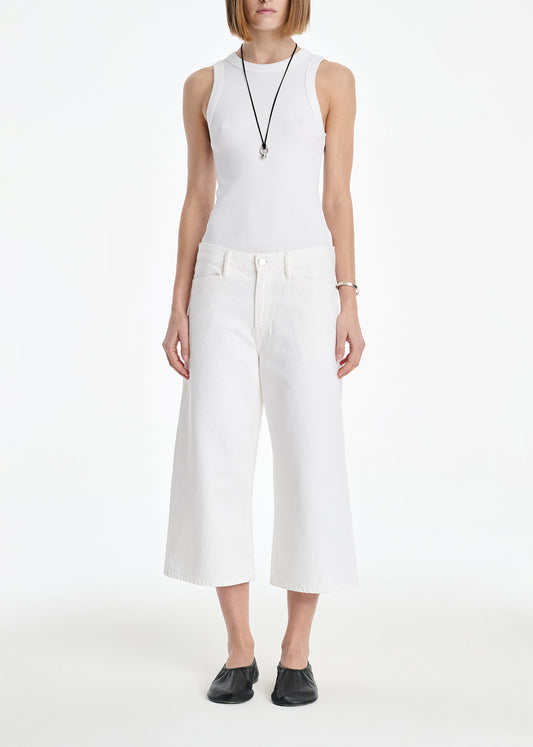 Person wearing a white sleeveless top and wide-leg pants on a white background