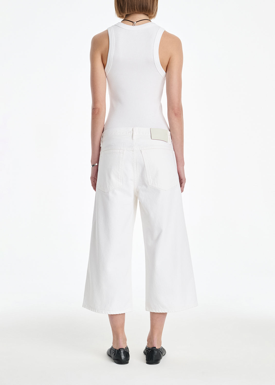 Person wearing a white sleeveless top and wide-leg pants on a white background