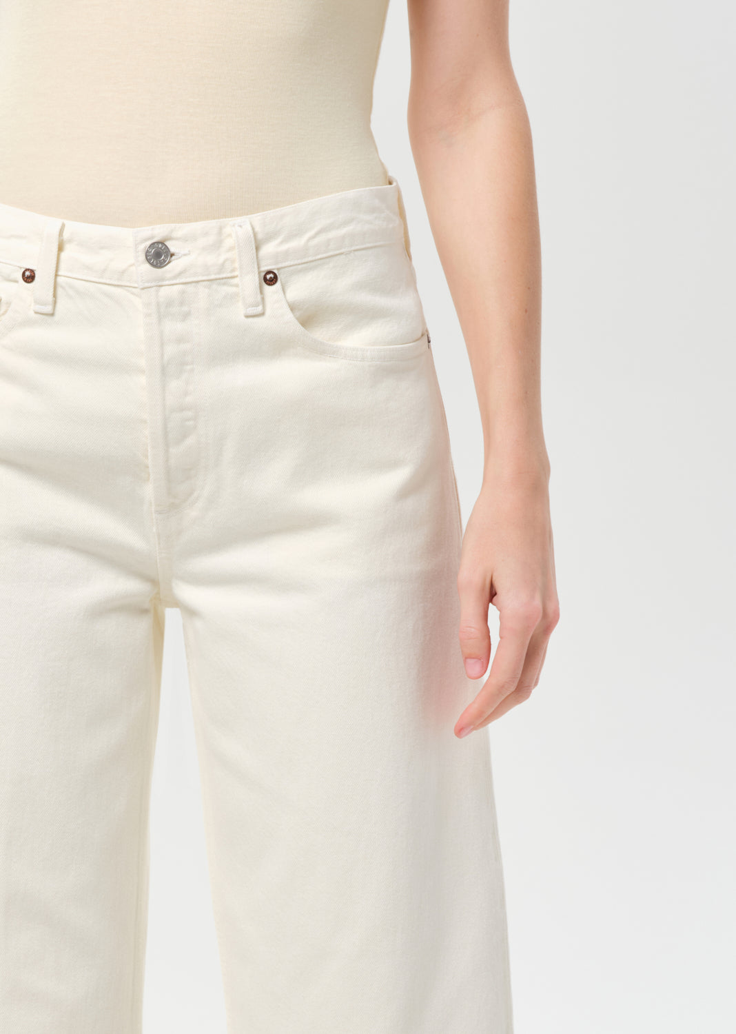 Close-up of a person wearing white jeans on a plain background