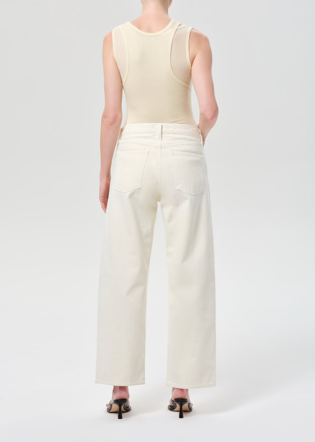 Person wearing a cream sleeveless top and wide-leg pants on a white background