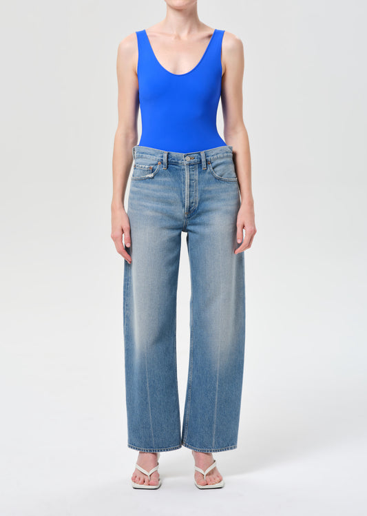 Person wearing a blue tank top and light blue jeans on a white background