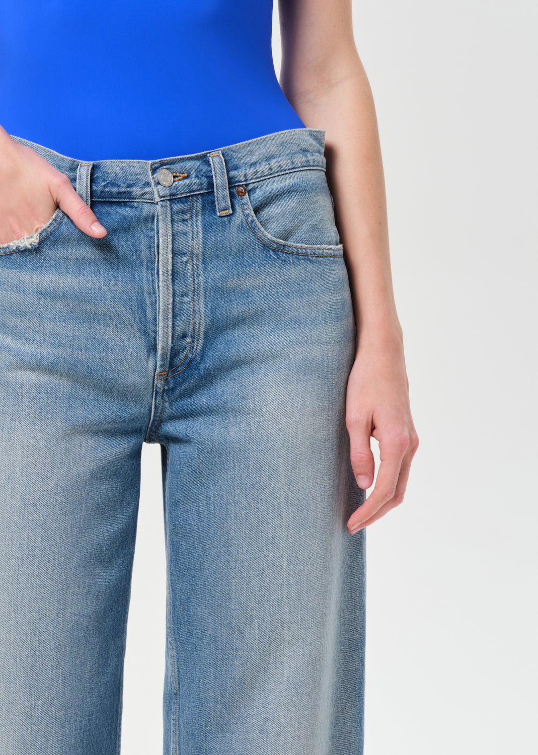 Person wearing blue jeans on a plain background