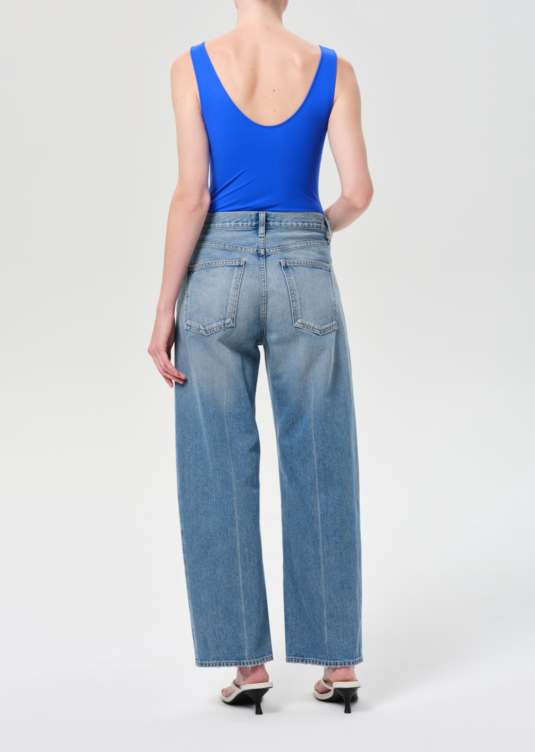 Person wearing blue jeans and a blue top on a white background