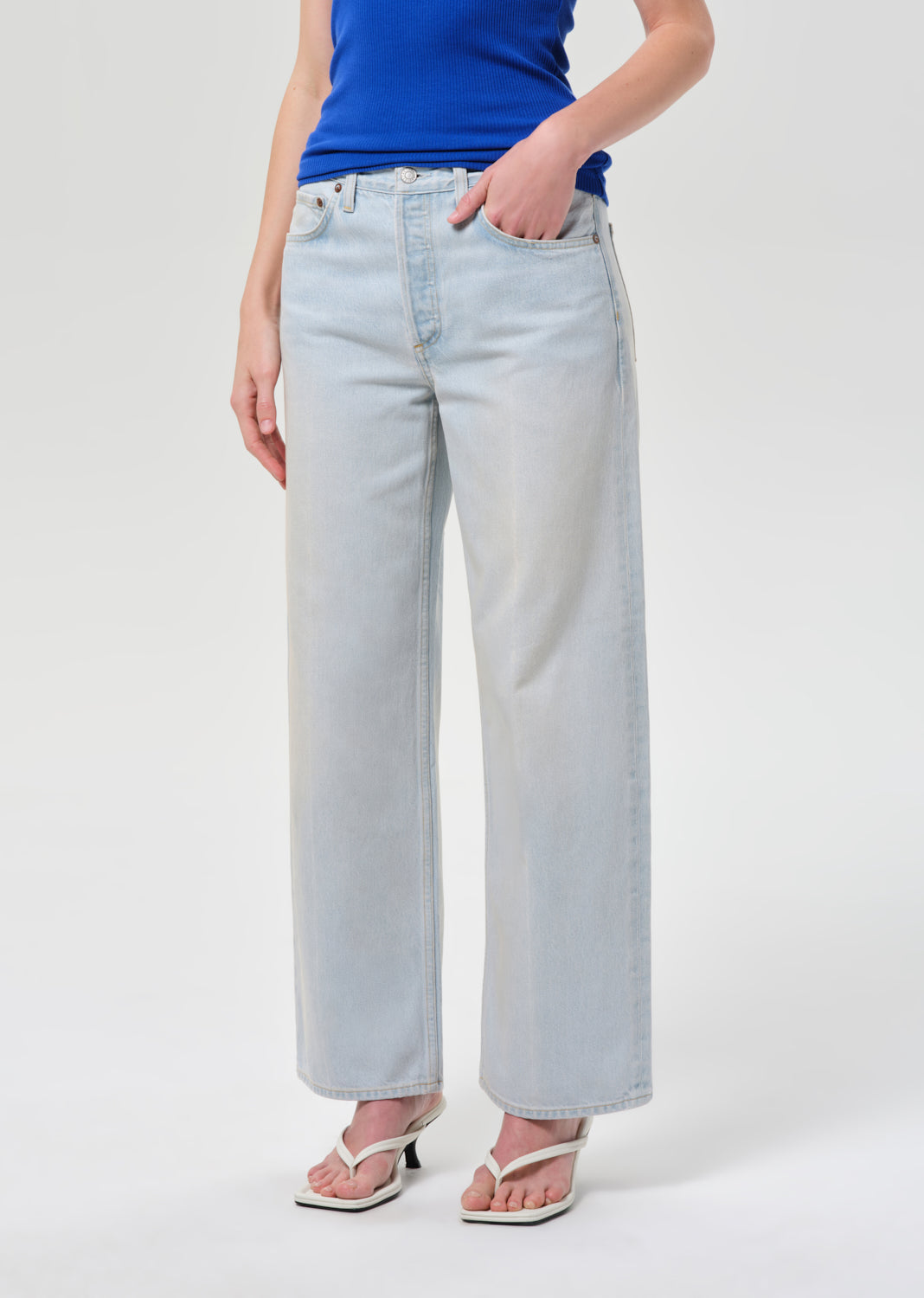 Person wearing light blue jeans and a blue top on a white background