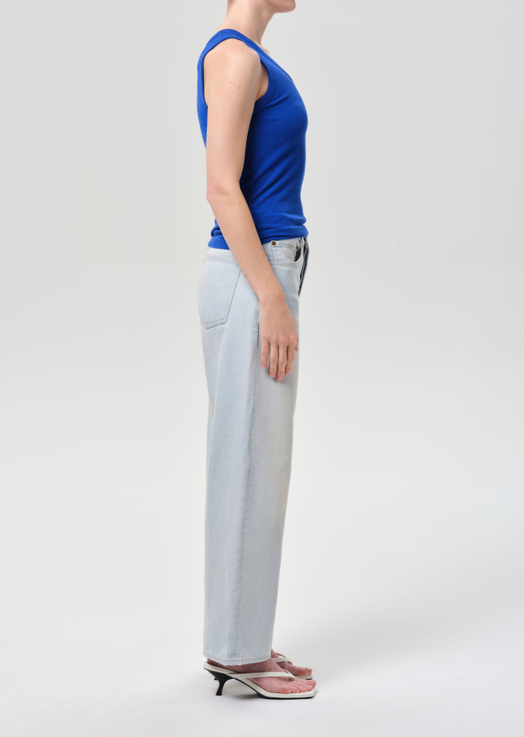 Person wearing a blue top and light gray pants on a white background