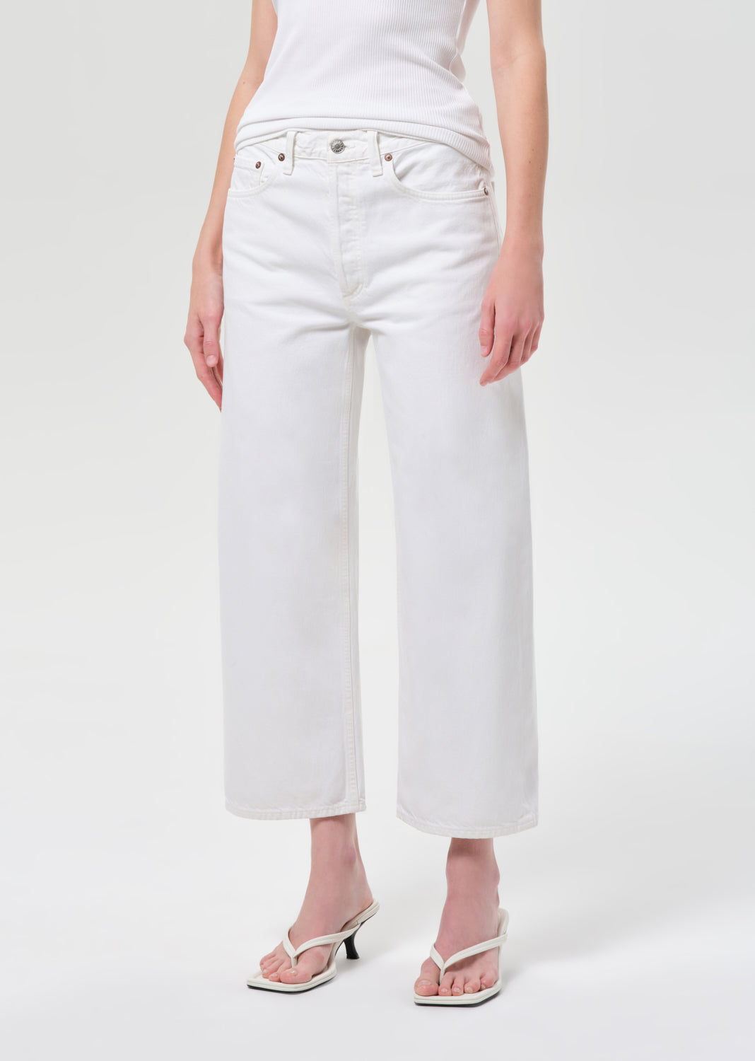 Person wearing white jeans on a plain background