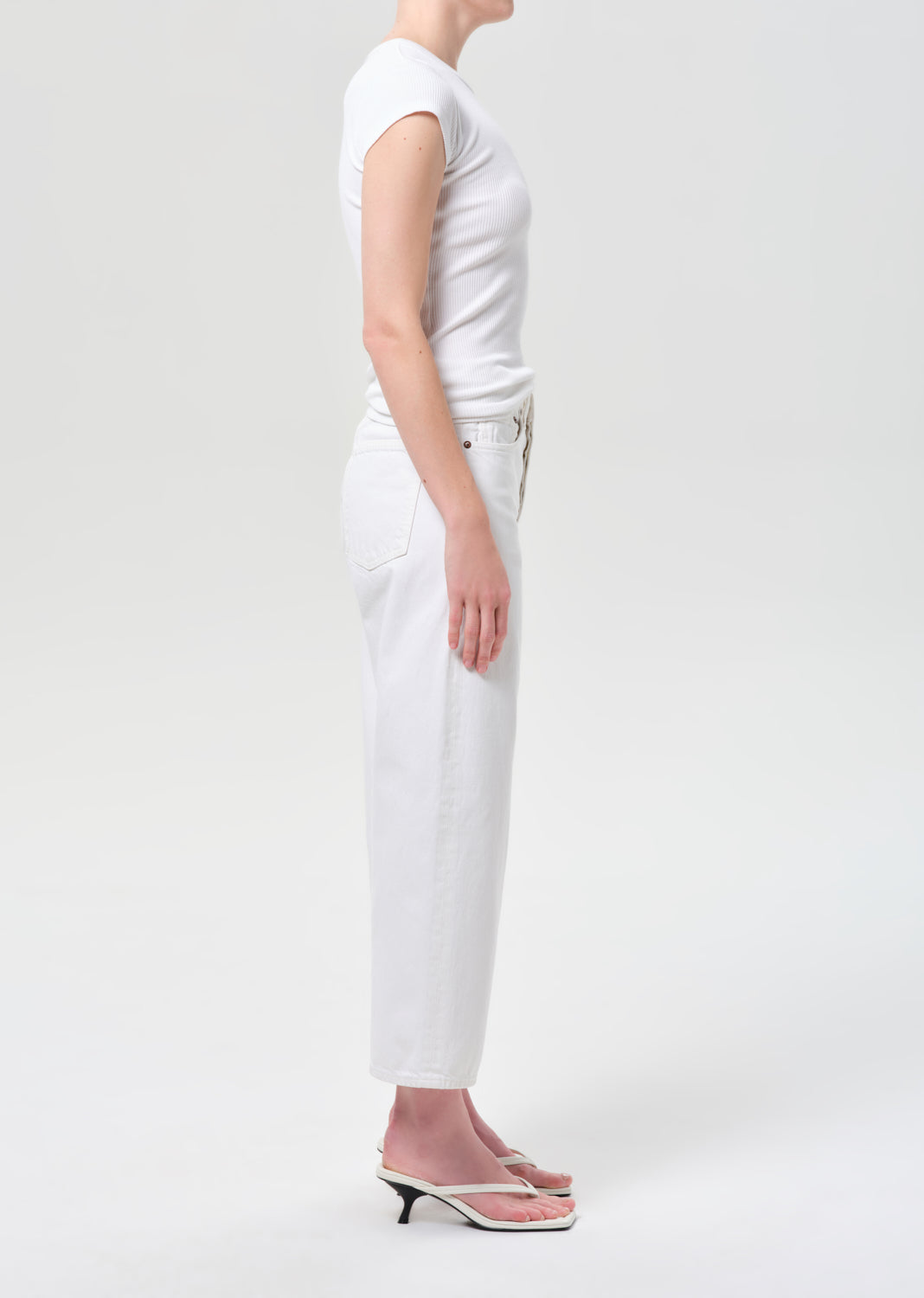 Person wearing a white t-shirt and pants on a light gray background