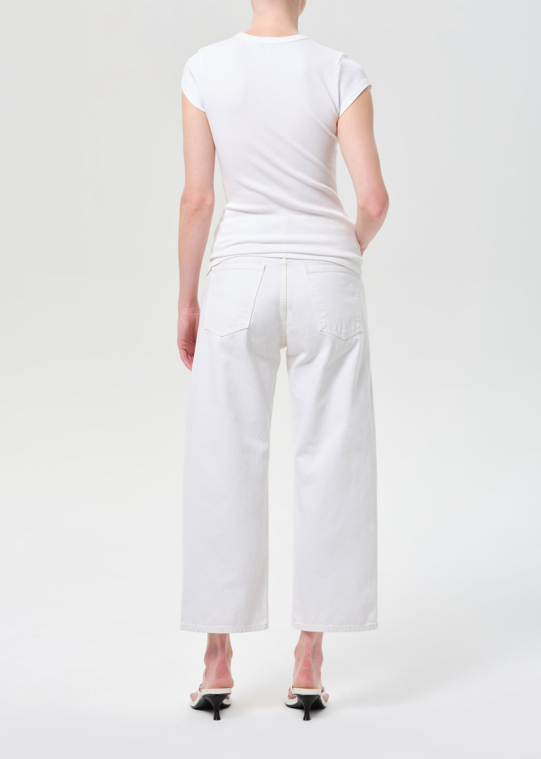 Person wearing a white t-shirt and white pants on a white background