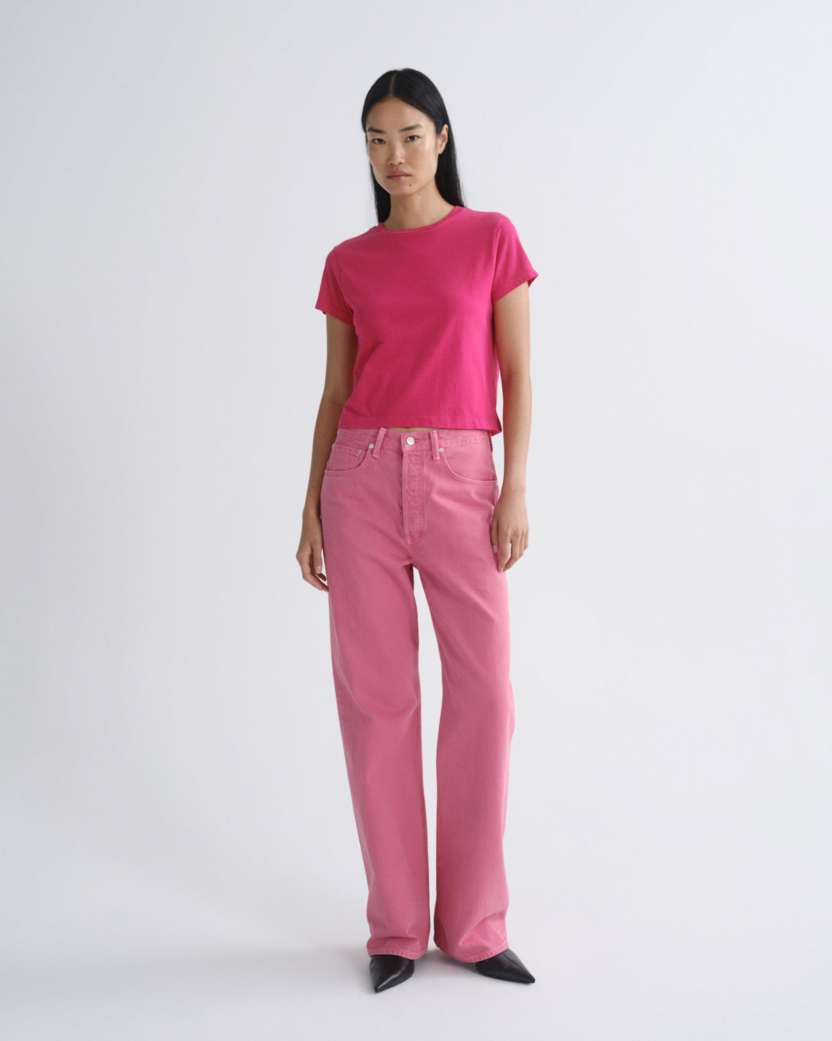 Person wearing a bright pink t-shirt and pants on a white background
