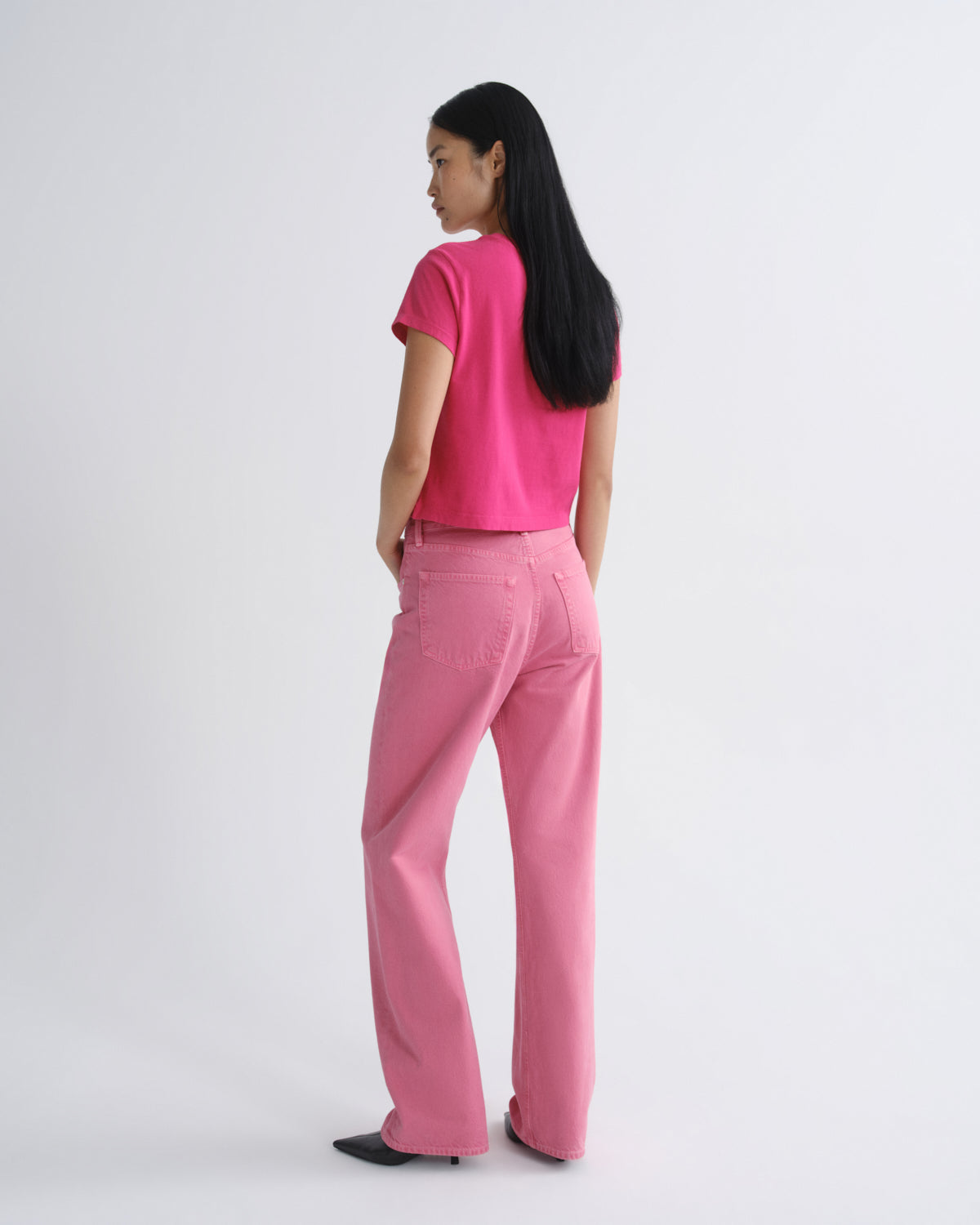 Person wearing a bright pink outfit on a white background