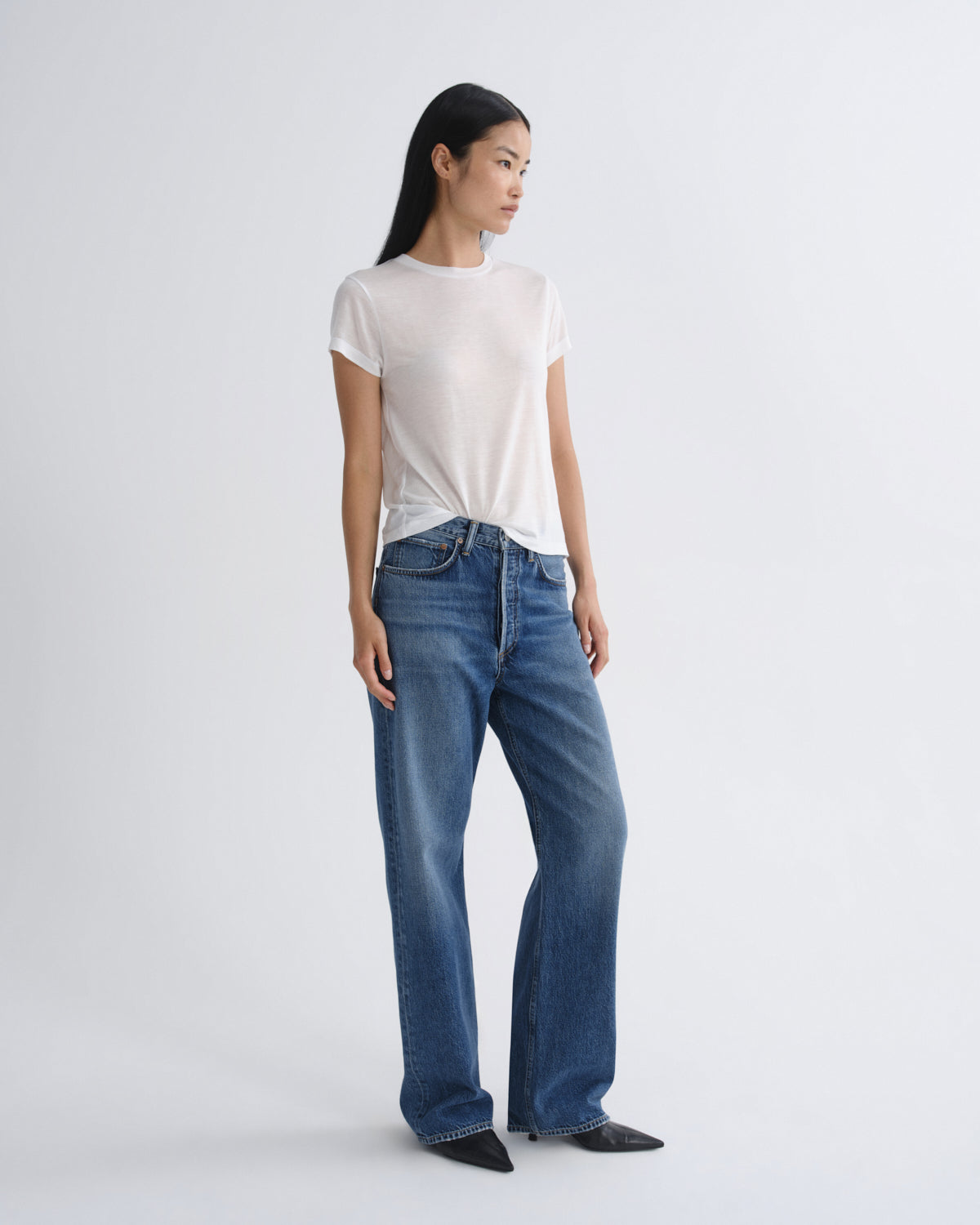 Woman wearing a white t-shirt and blue jeans on a white background