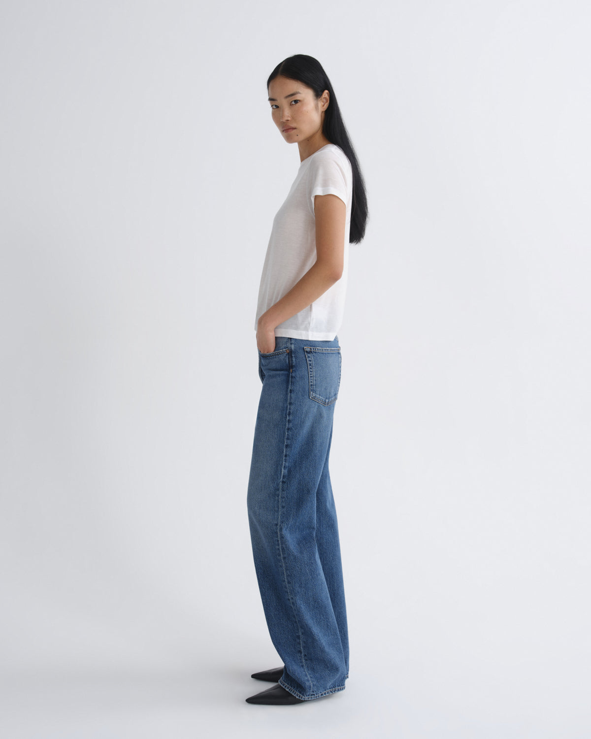 Woman wearing a white t-shirt and blue jeans on a white background