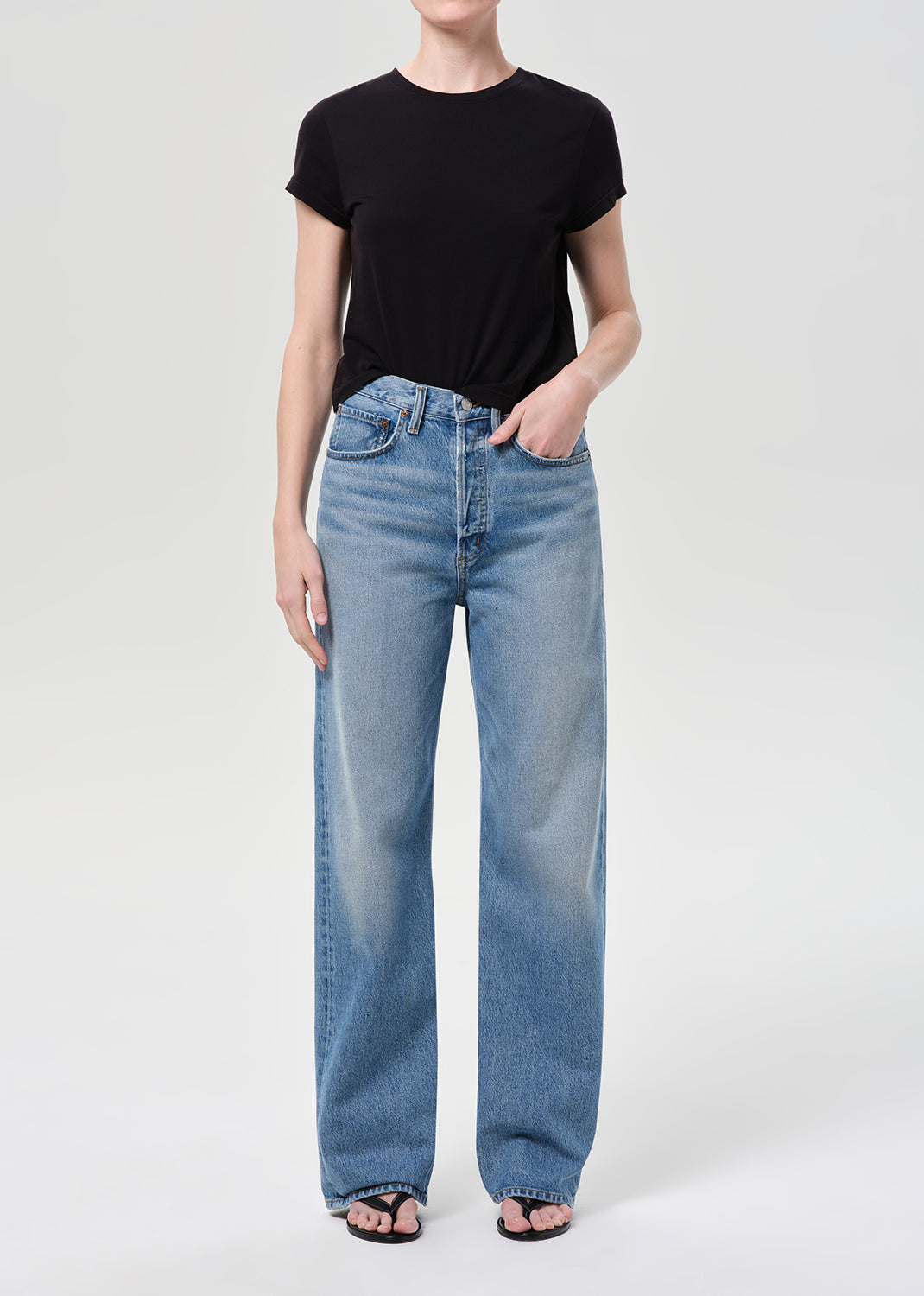 Person wearing a black t-shirt and light blue jeans on a white background