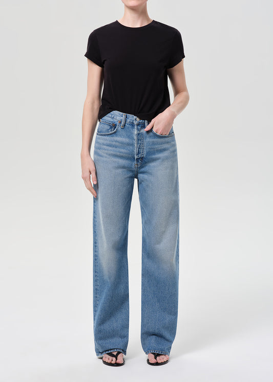 Person wearing a black t-shirt and light blue jeans on a white background