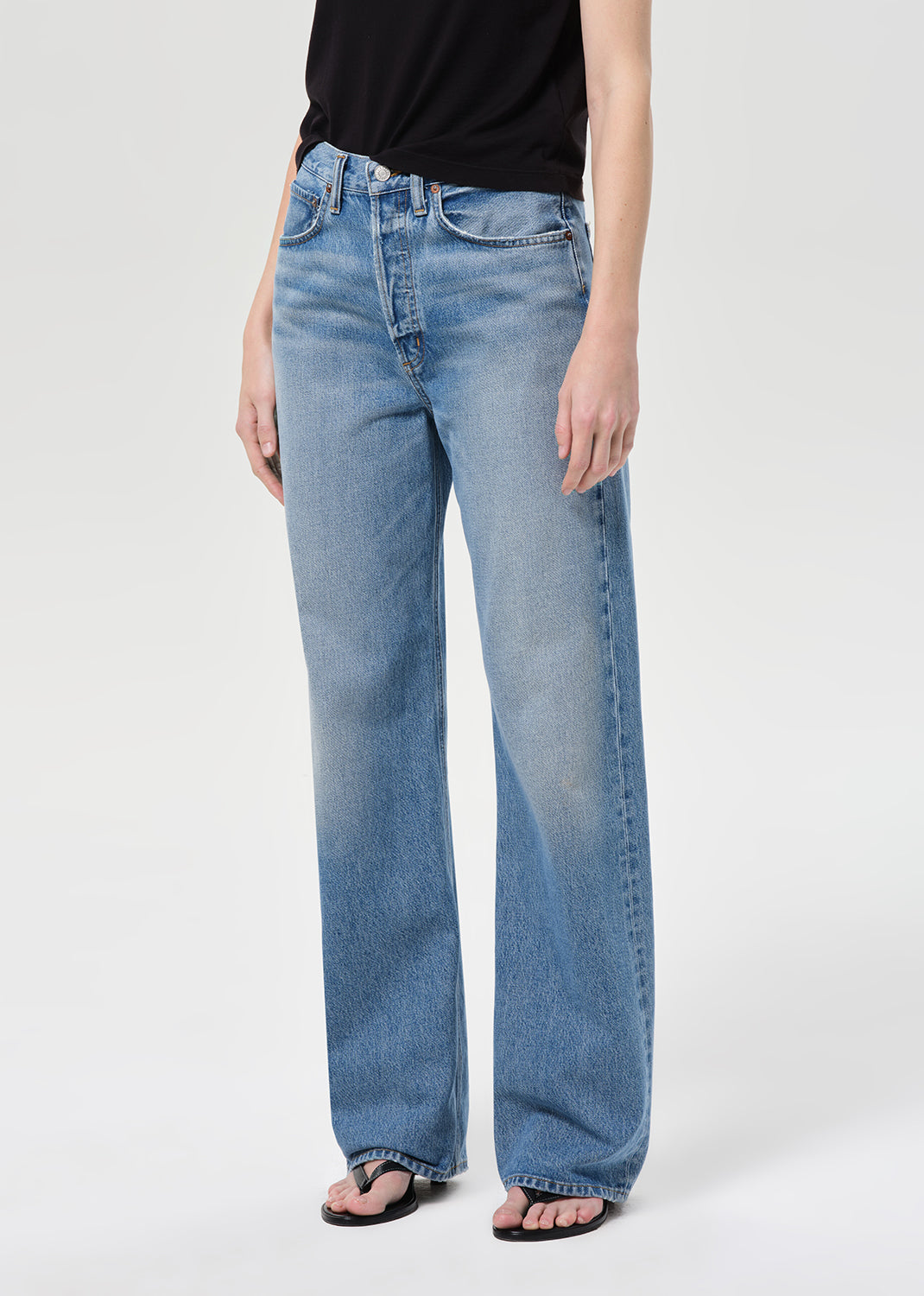 Person wearing light blue jeans on a white background