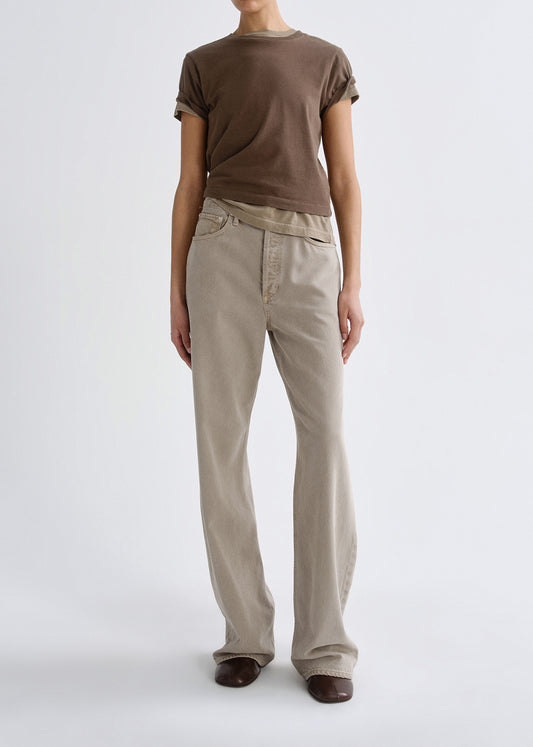 Person wearing a brown t-shirt and beige pants on a grey background