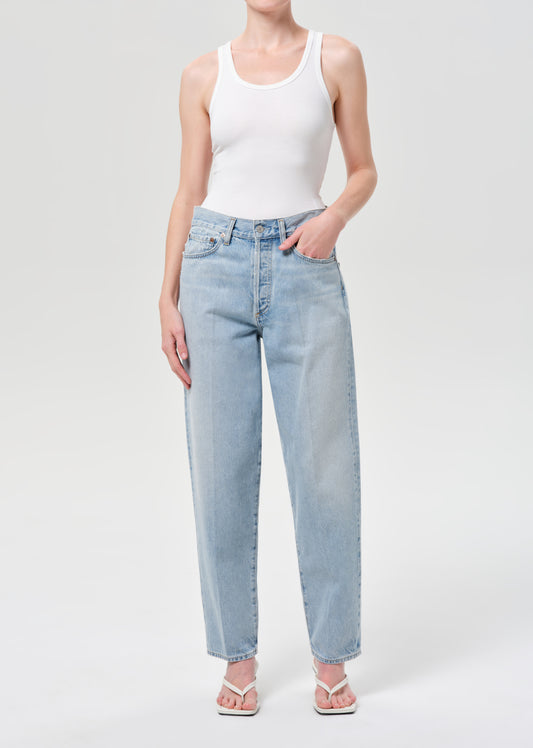 Person wearing a white tank top and light blue jeans on a white background