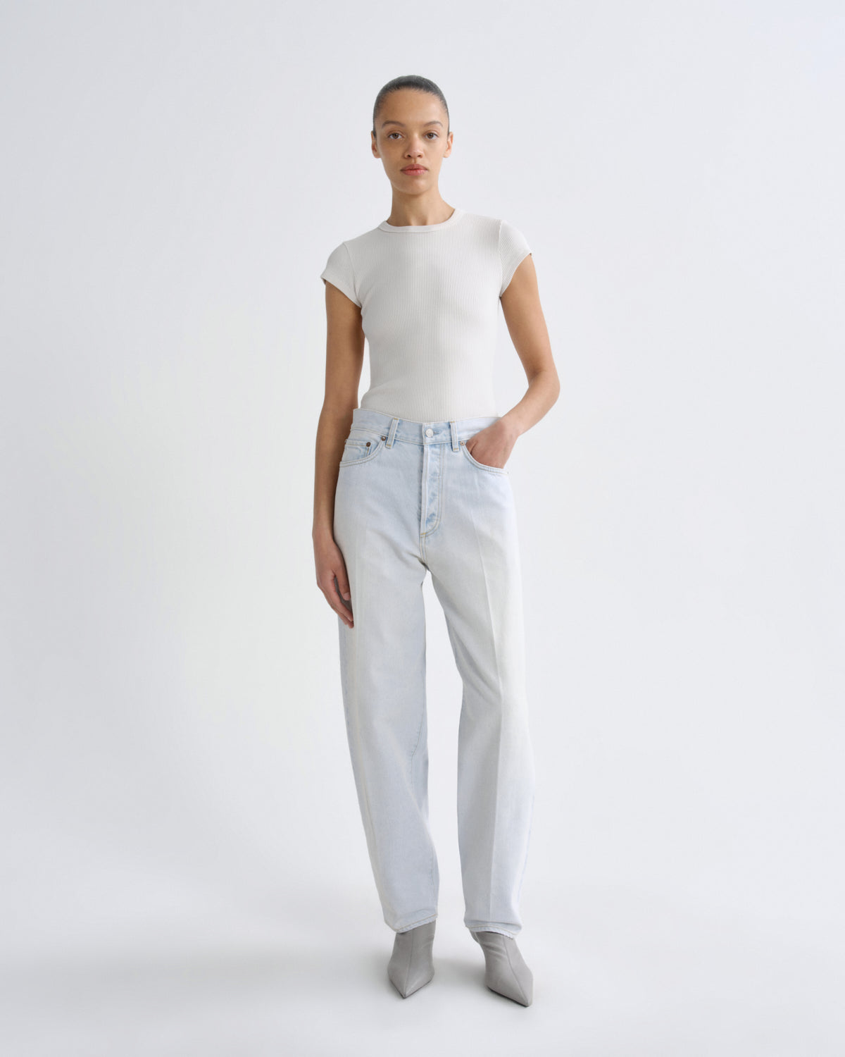 Person wearing a white t-shirt and light blue jeans on a white background