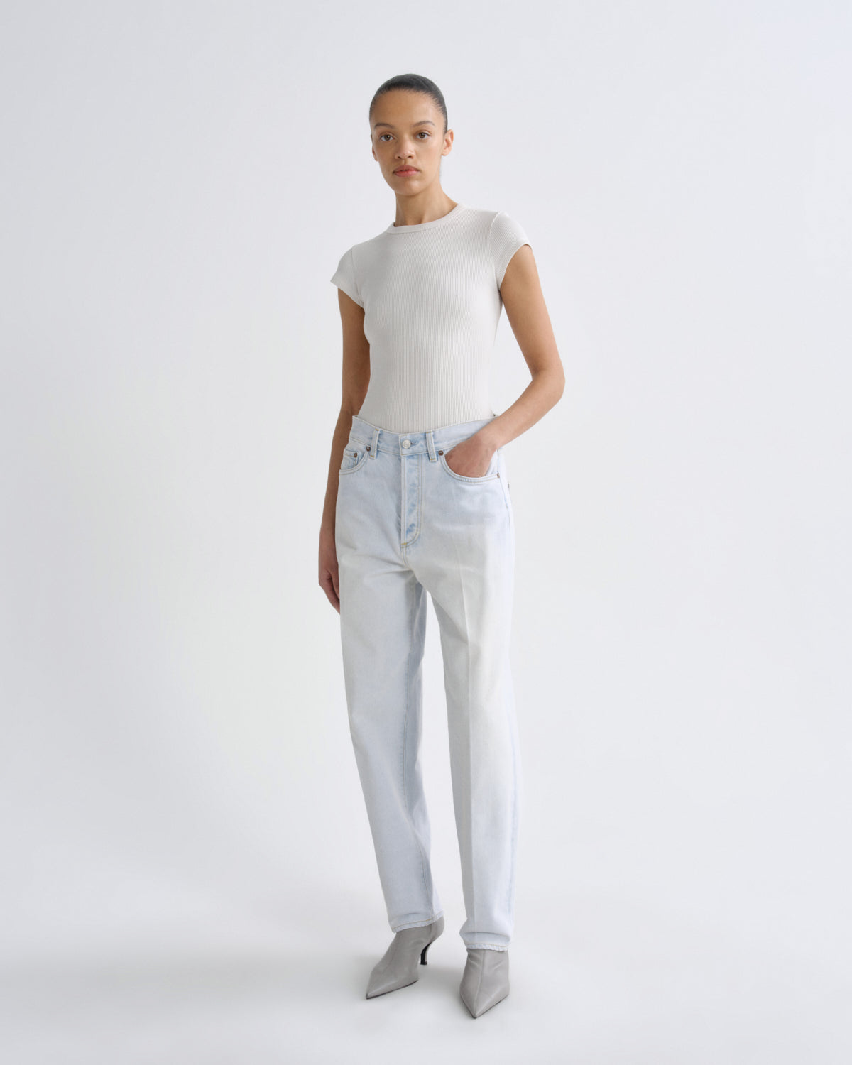 Woman wearing a white top and light blue jeans on a white background