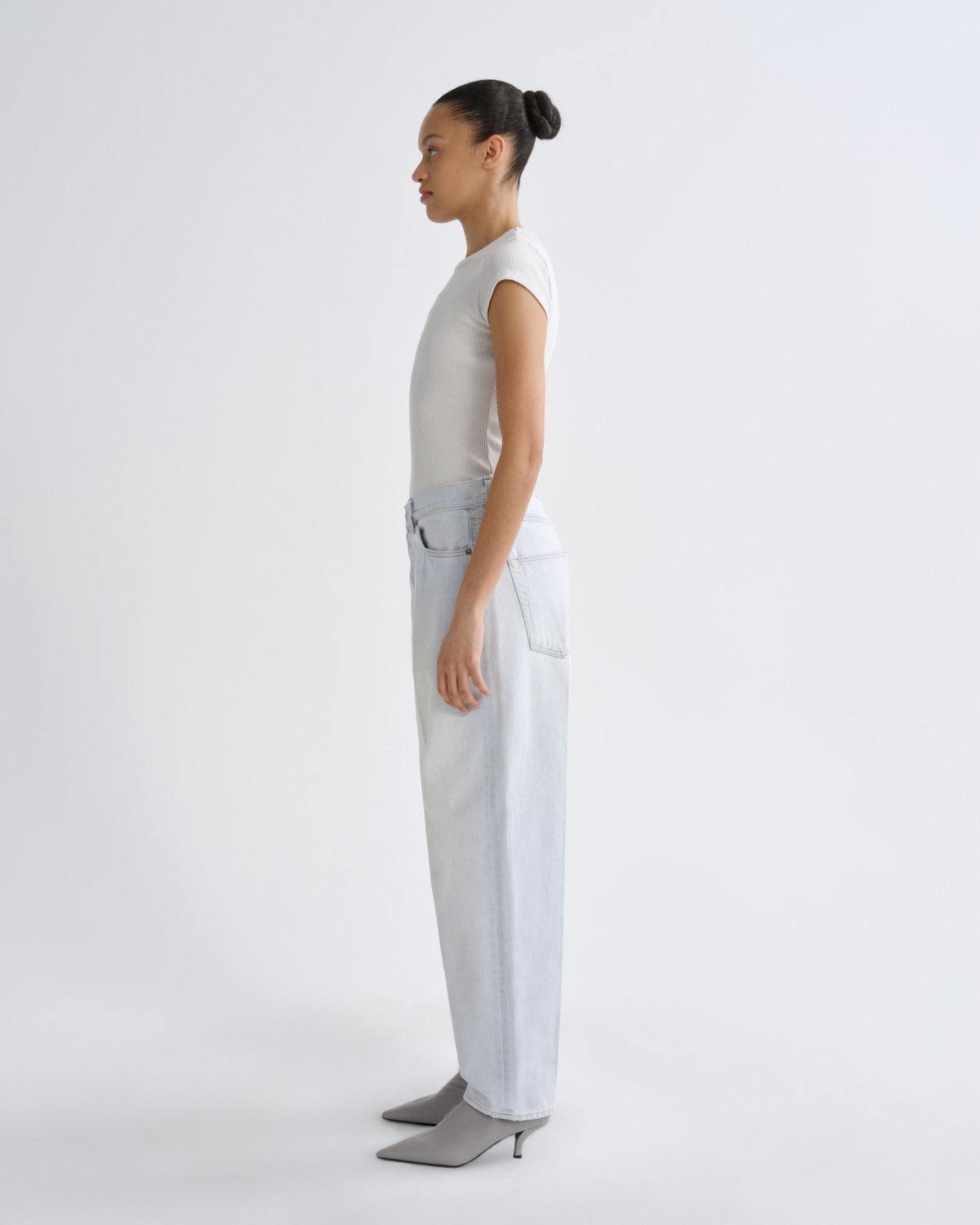 Person wearing a white top and light blue pants on a white background