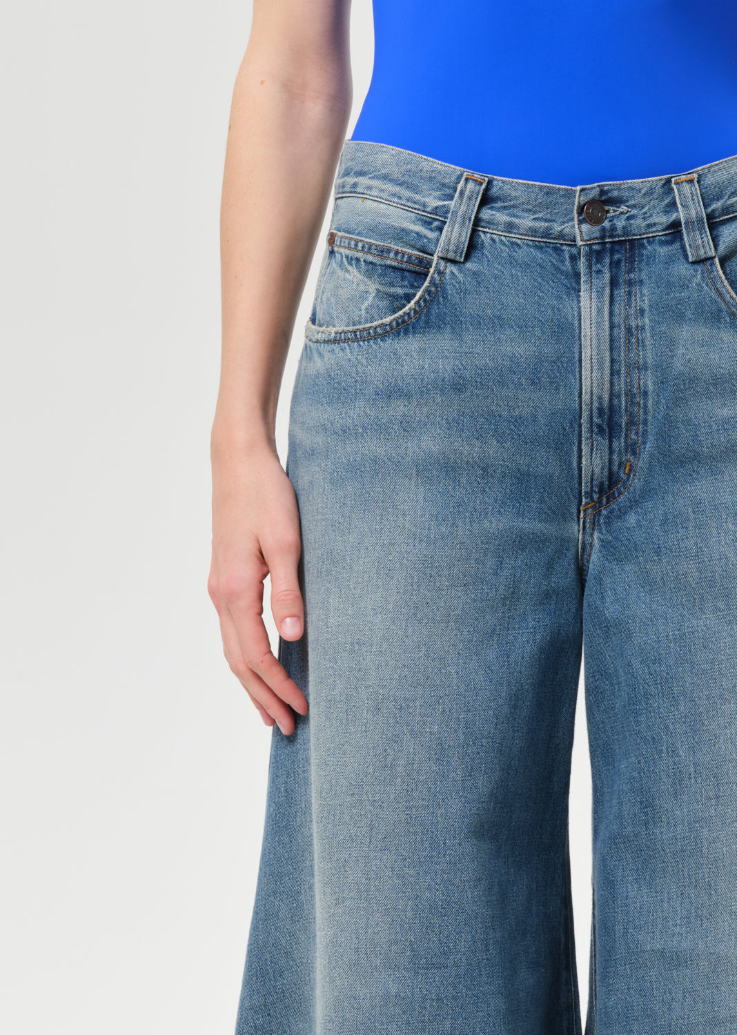 Person wearing blue jeans on a plain background