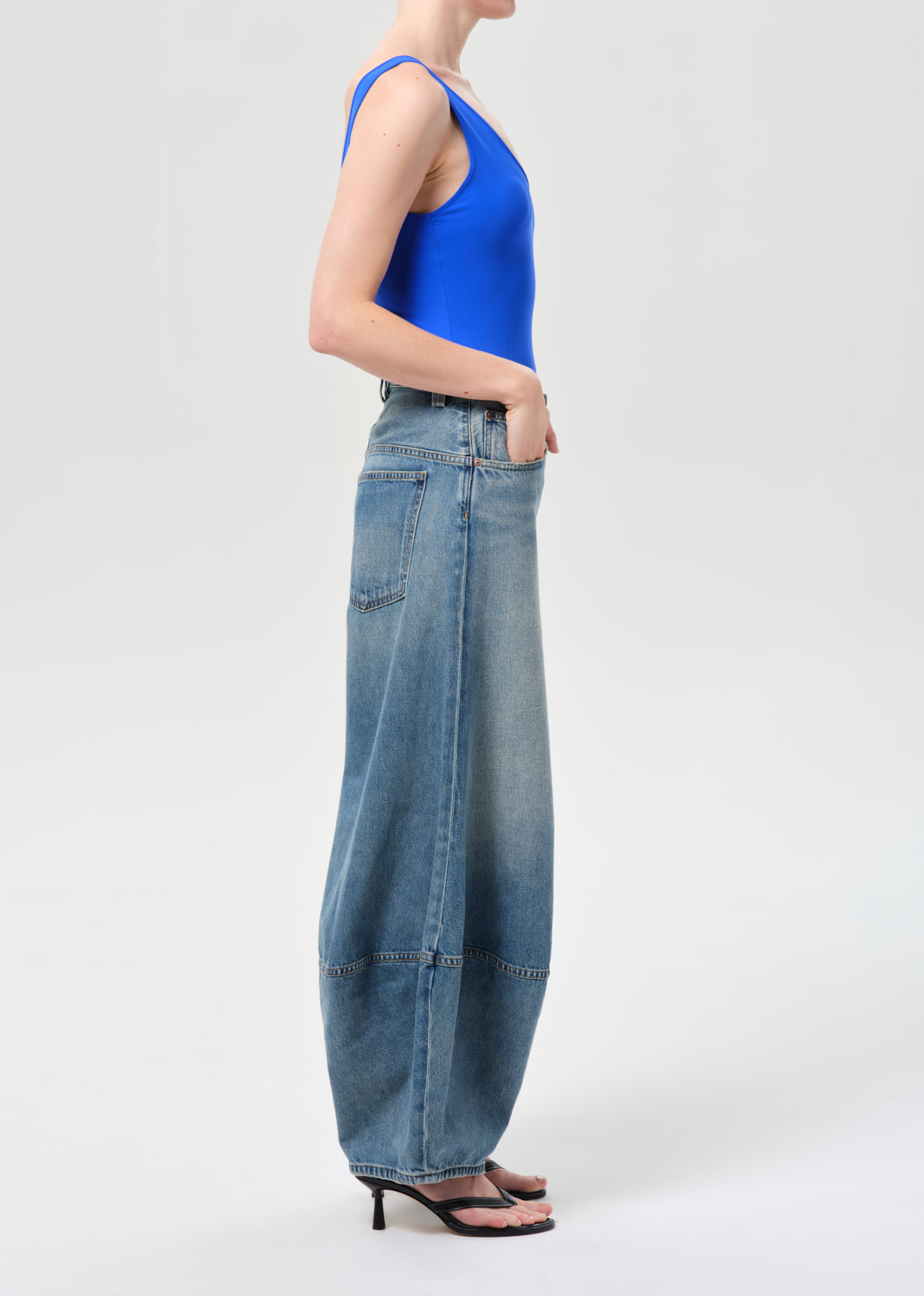 Person wearing a blue sleeveless top and wide-leg jeans on a white background